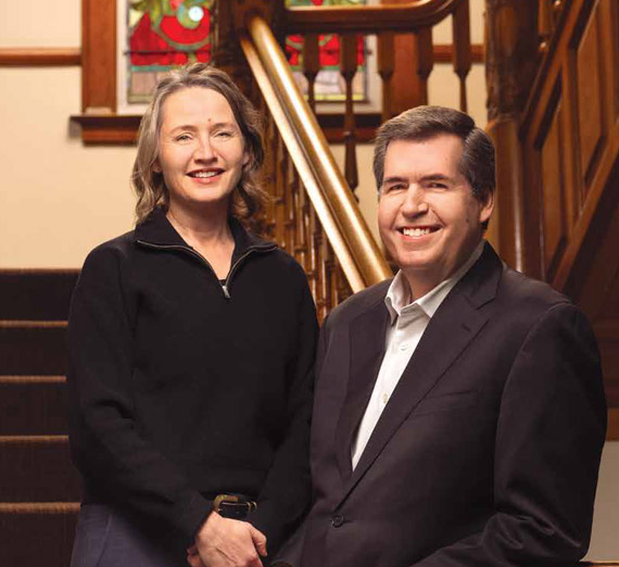 two individuals stand side by side with shovels, one wrapped in blue and the other in purple